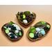 Examples of three handmade acacia bowls displaying a green and natural colored blend of botanicals. Bowl shapes are heart, oval, and shell.